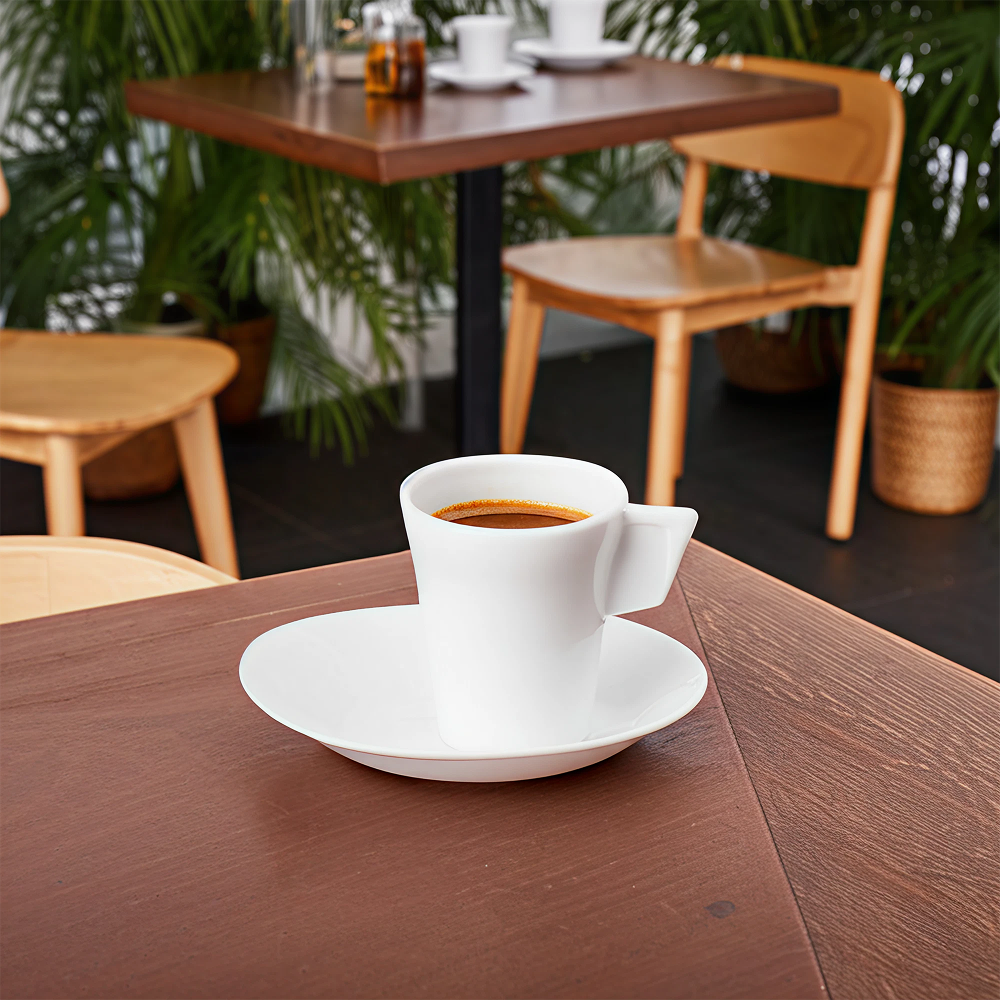 Chávena de café com pires Liffe branco em um ambiente de café