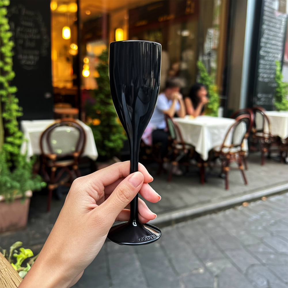 Copo de champanhe Liffe preto de 12 cl em um ambiente externo de restaurante